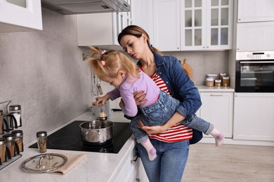 Photo of Busy housewife cooking with her little daughter in kitchen