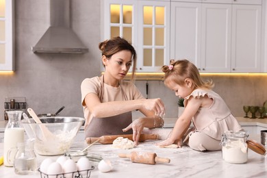 Photo of Housewife cooking with her little daughter at marble table in kitchen