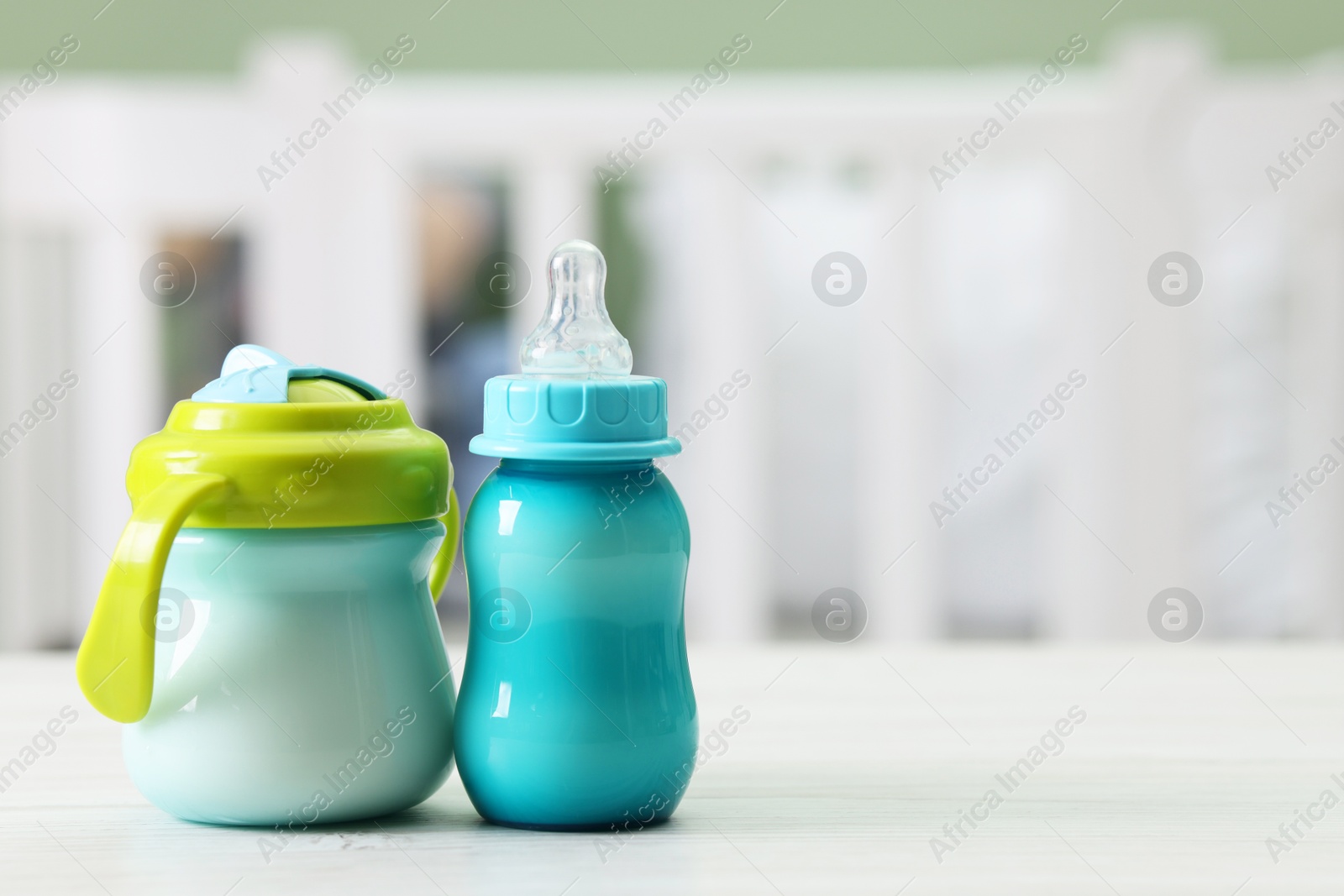 Photo of Feeding bottles with milk on white wooden table indoors, space for text