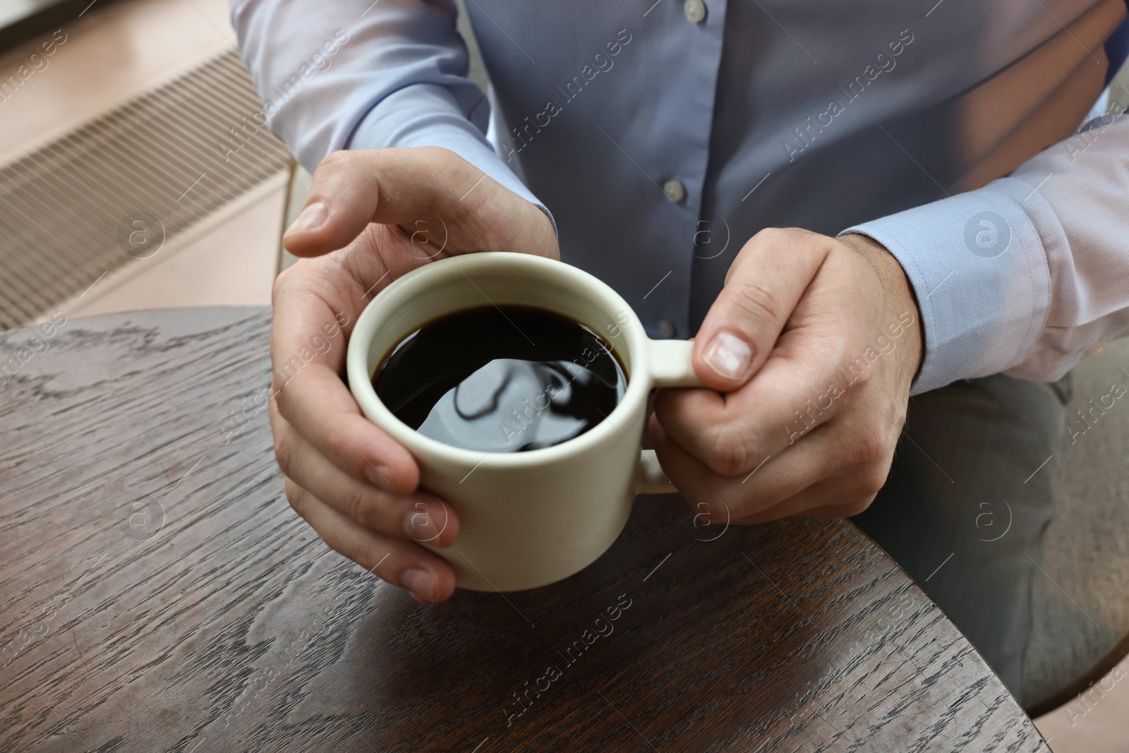 Photo of Businessman having coffee break at wooden table in cafe, closeup