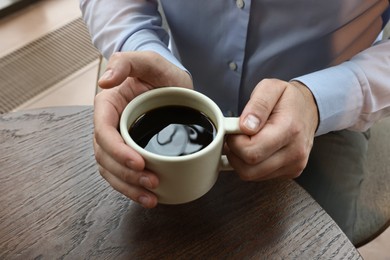 Photo of Businessman having coffee break at wooden table in cafe, closeup