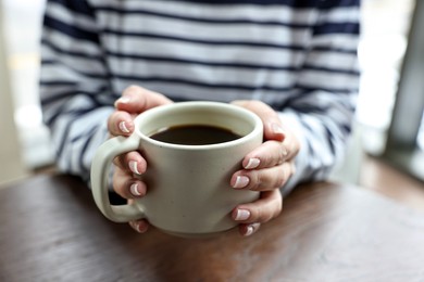 Photo of Woman having coffee break at wooden table in cafe, closeup