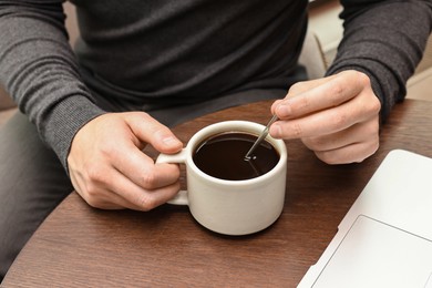 Photo of Man having coffee break at wooden table in cafe, closeup