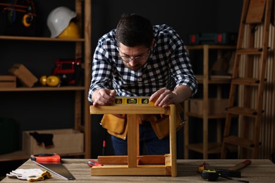 Photo of Repairman checking stool level at table in workshop