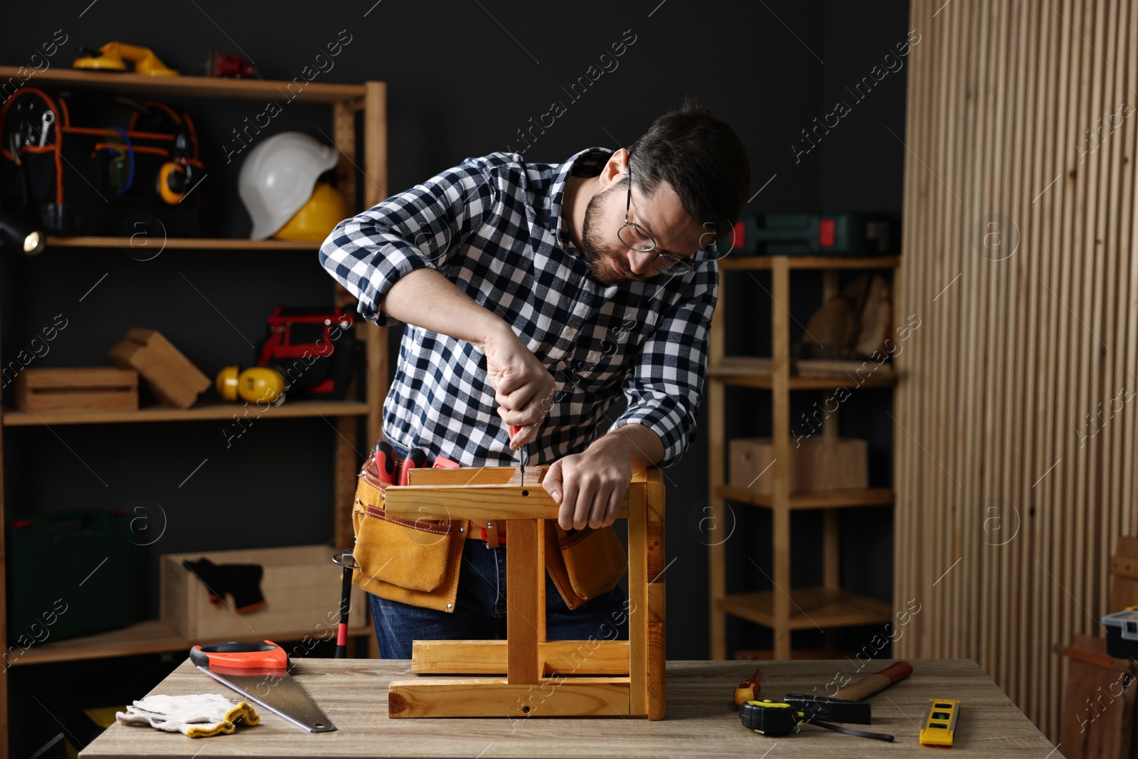 Photo of Carpenter repairing stool at table in workshop