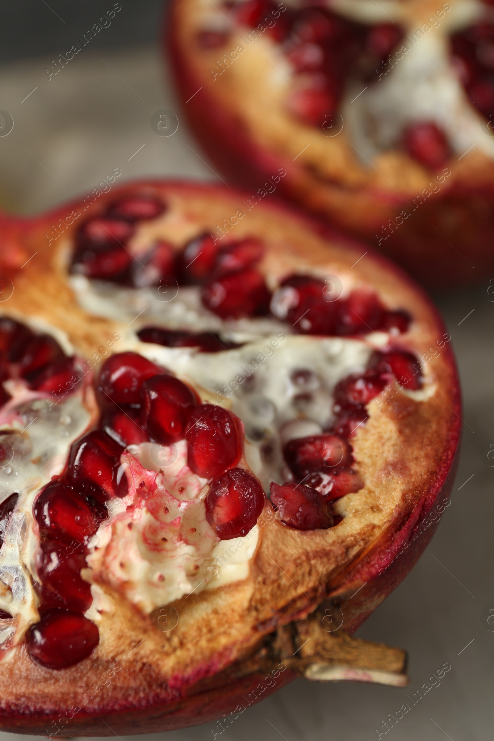 Photo of Fresh juicy pomegranates on grey table, closeup