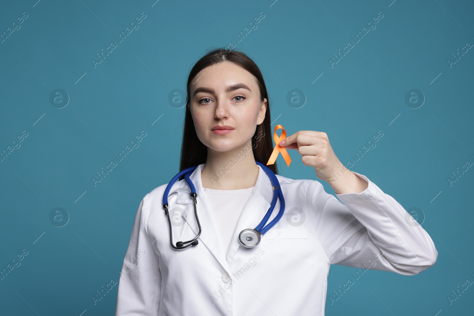 Photo of Multiple Sclerosis awareness. Doctor holding orange ribbon on light blue background