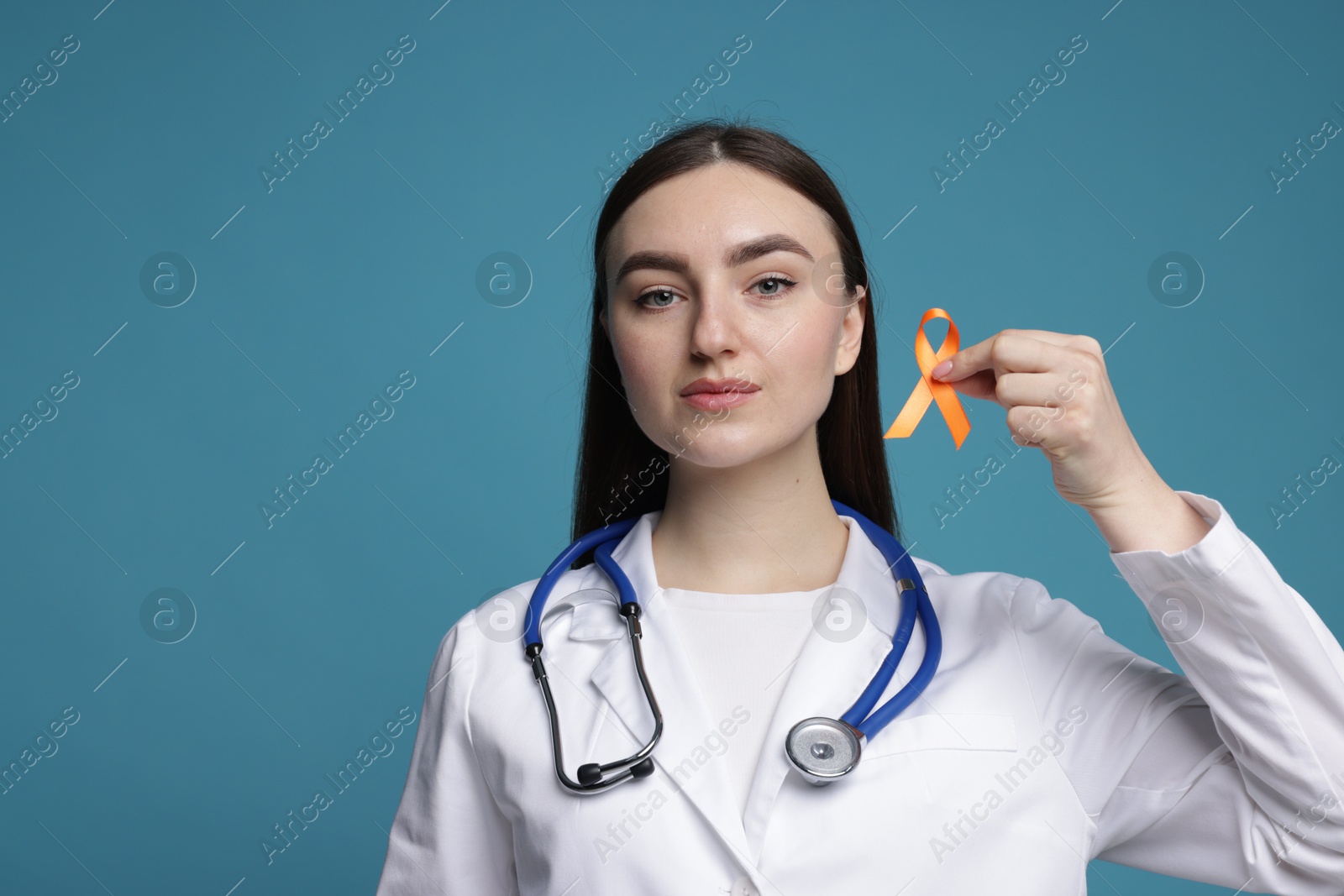 Photo of Multiple Sclerosis awareness. Doctor holding orange ribbon on light blue background