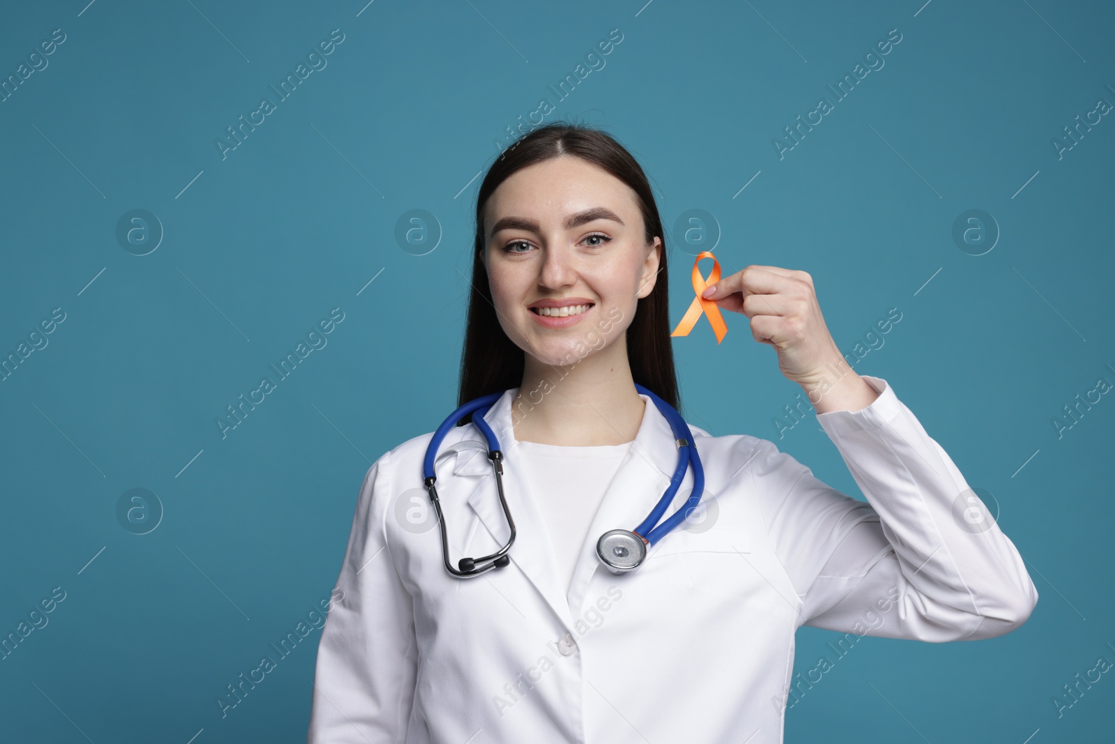 Photo of Multiple Sclerosis awareness. Happy doctor holding orange ribbon on light blue background