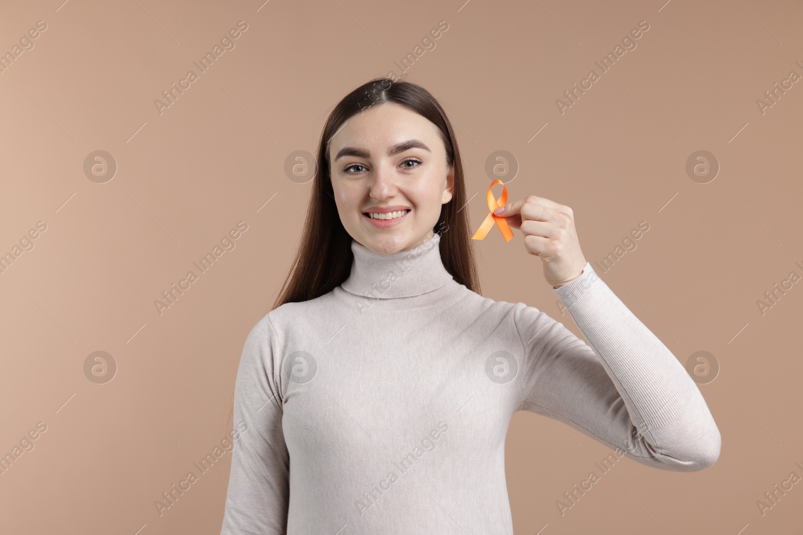 Photo of Multiple Sclerosis awareness. Happy young woman holding orange ribbon on beige background