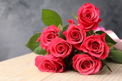 Photo of Beautiful red roses on wooden table, closeup