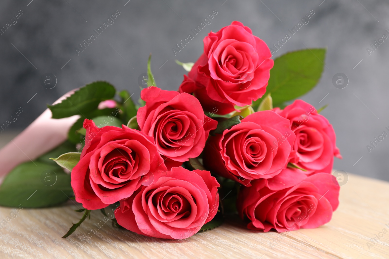 Photo of Beautiful red roses on wooden table, closeup