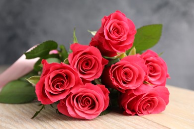 Photo of Beautiful red roses on wooden table, closeup