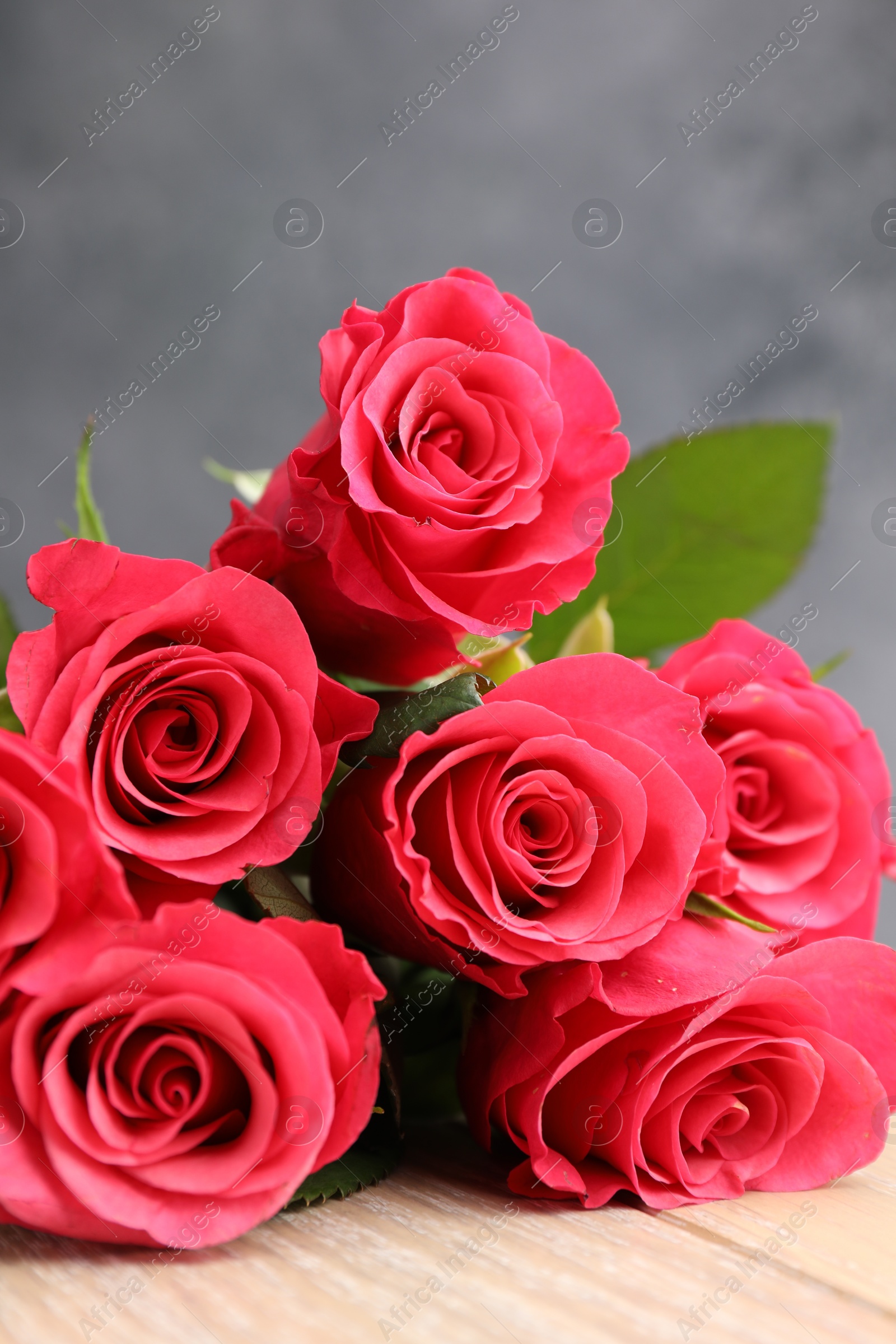 Photo of Beautiful red roses on wooden table, closeup