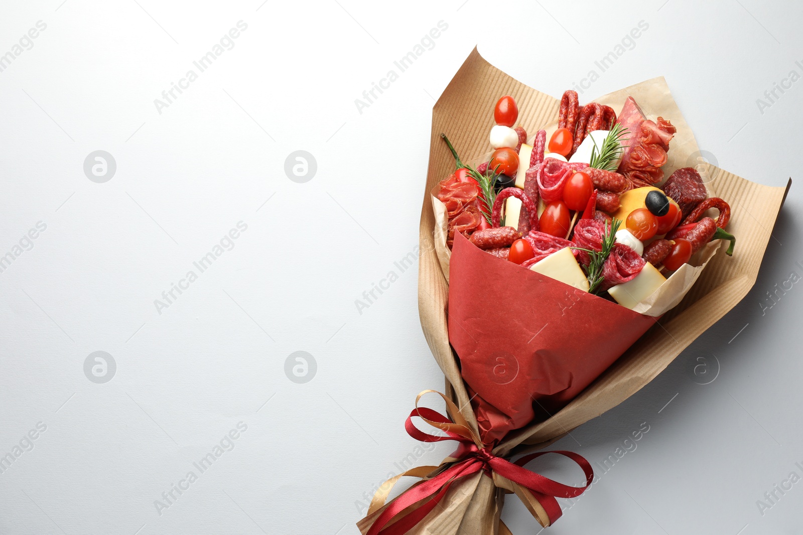 Photo of Beautiful edible bouquet with meat, cheese and tomatoes on white background, top view. Space for text