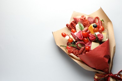 Photo of Beautiful edible bouquet with meat, cheese and tomatoes on white background, top view. Space for text