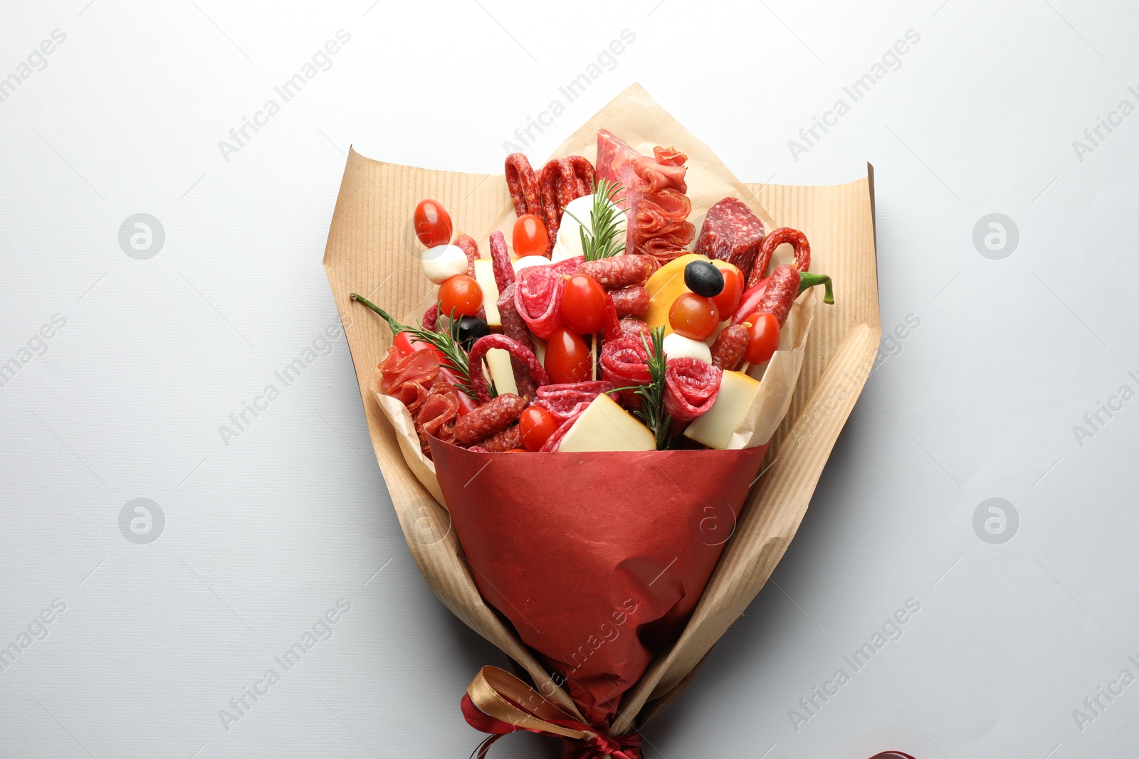 Photo of Beautiful edible bouquet with meat, cheese and tomatoes on white background, top view