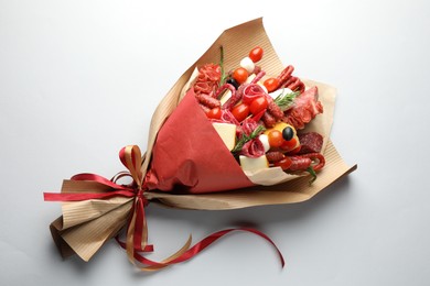 Photo of Beautiful edible bouquet with meat, cheese and tomatoes on white background, top view