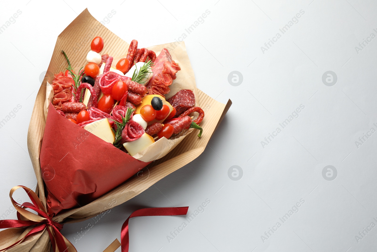 Photo of Beautiful edible bouquet with meat, cheese and tomatoes on white background, top view. Space for text