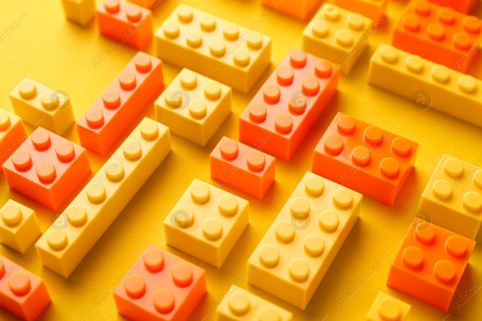 Photo of Constructor toy. Many building blocks on yellow background, closeup