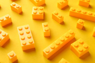 Photo of Constructor toy. Many building blocks on yellow background, closeup