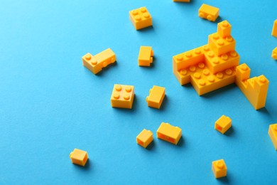 Photo of Constructor toy. Many yellow building blocks on light blue background, space for text