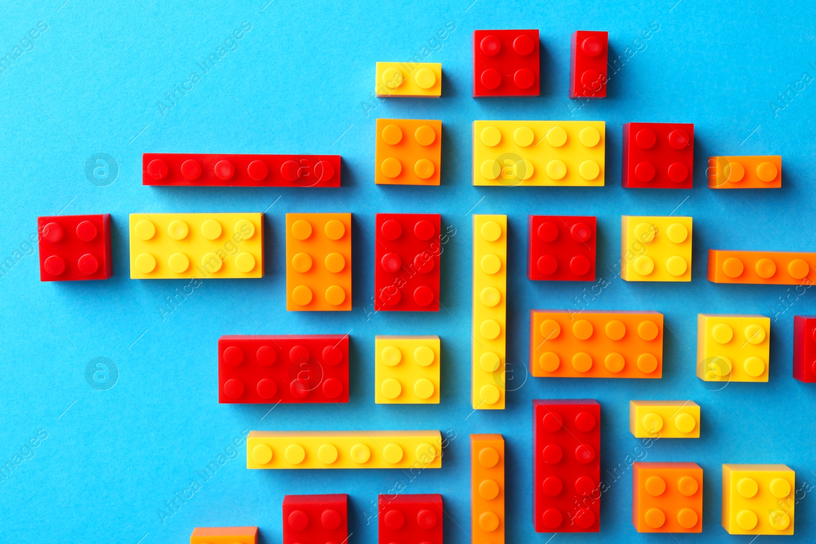 Photo of Constructor toy. Many colorful building blocks on light blue background, flat lay