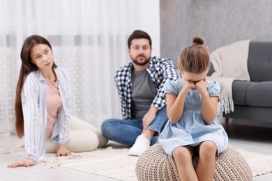 Photo of Resentful little girl crying near her parents at home. Family dispute