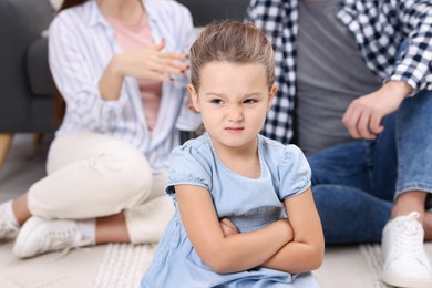 Photo of Resentful little girl and her parents at home. Family dispute