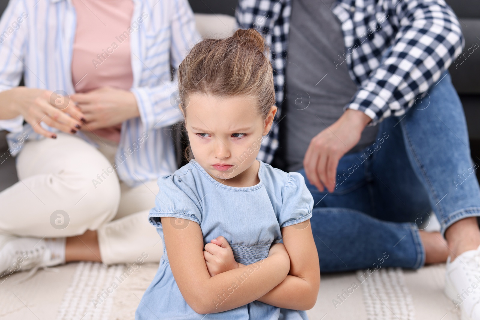 Photo of Resentful little girl and her parents at home. Family dispute