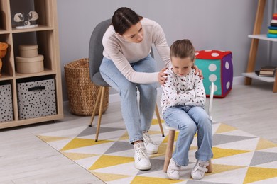 Photo of Resentful little girl and her mother arguing at home