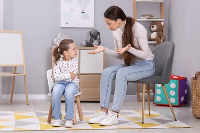 Photo of Resentful little girl and her mother arguing at home