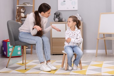 Photo of Resentful little girl and her mother arguing at home