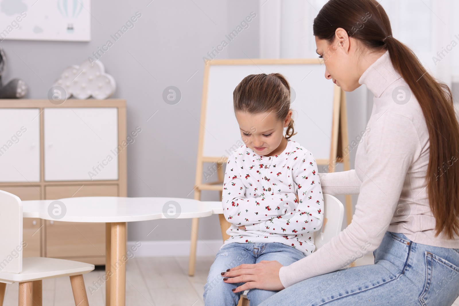 Photo of Resentful little girl and her mother at home, space for text. Family dispute