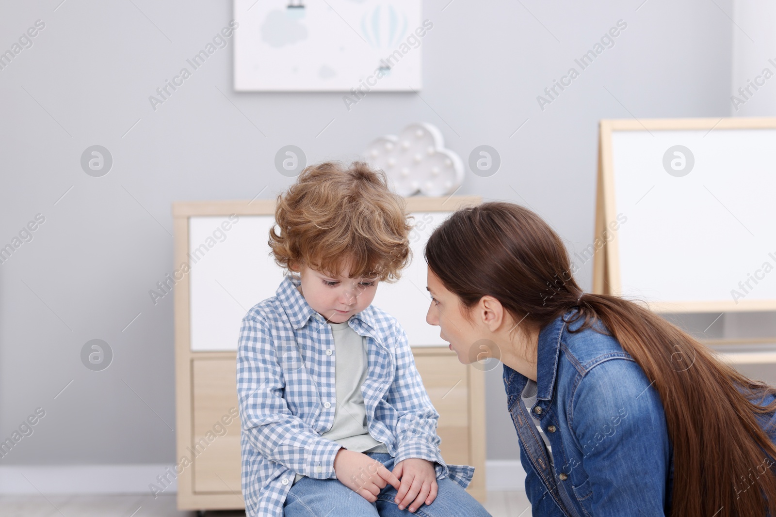 Photo of Resentful little boy and his mother arguing at home