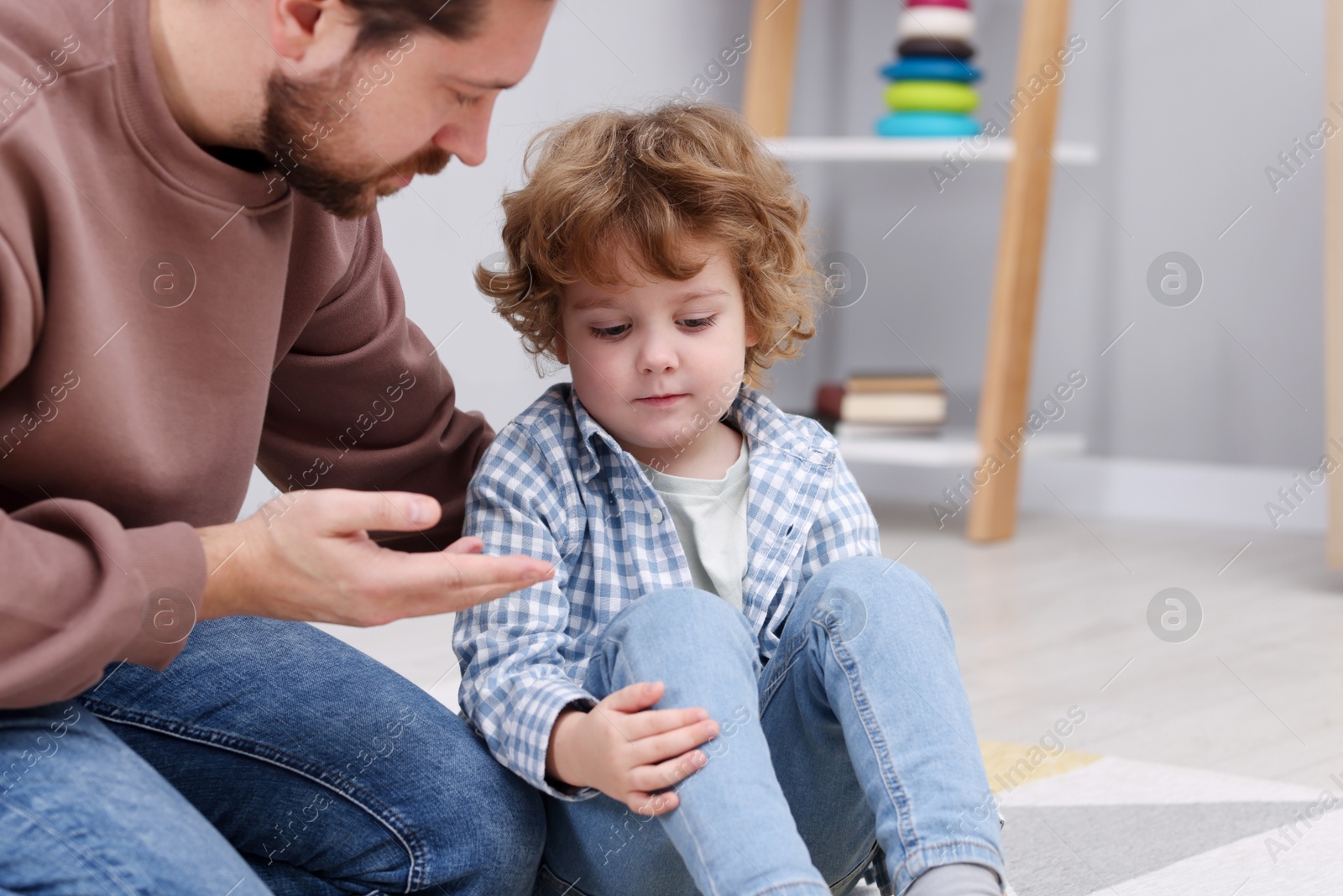 Photo of Resentful little boy and his father arguing at home, space for text