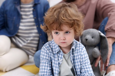 Photo of Resentful little boy and his parents arguing at home