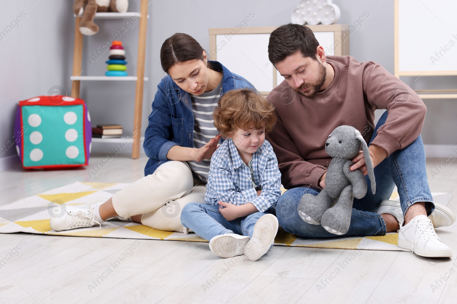 Photo of Resentful little boy and his parents arguing at home