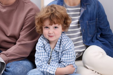 Photo of Resentful little boy and his parents arguing at home