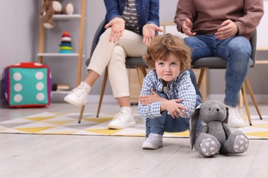 Photo of Resentful little boy and his parents arguing at home