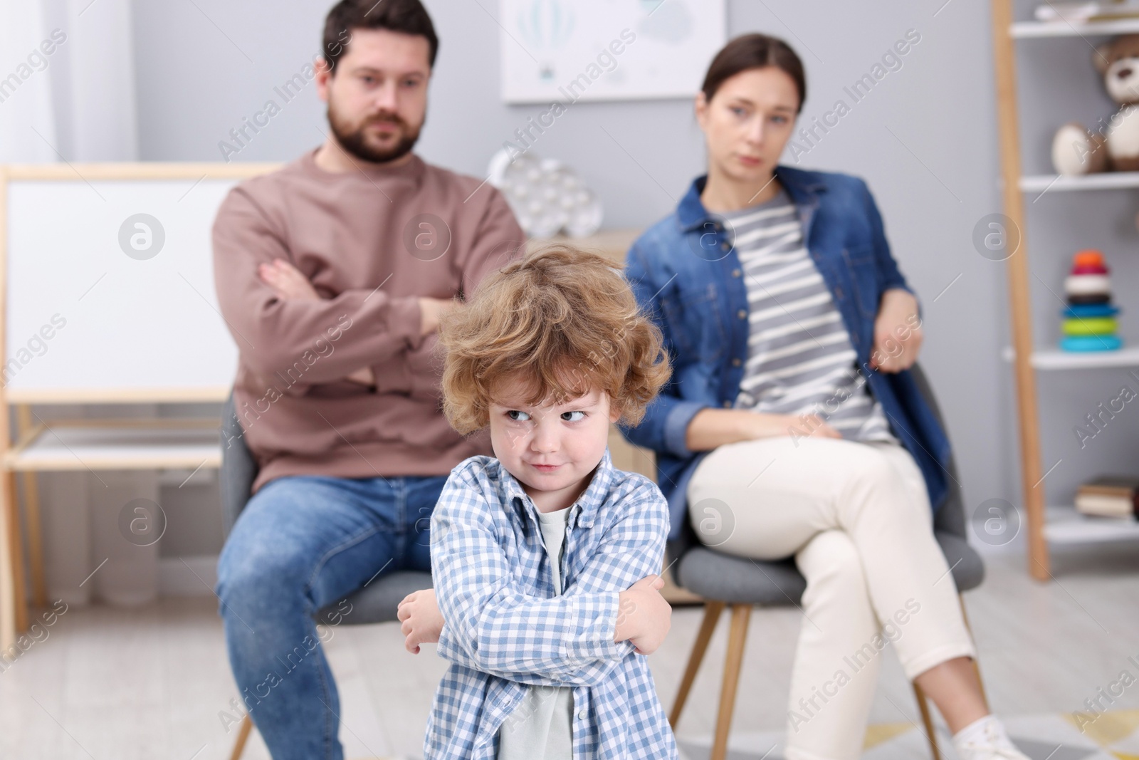 Photo of Resentful little boy and his parents arguing at home