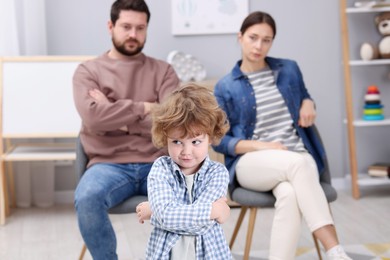 Photo of Resentful little boy and his parents arguing at home