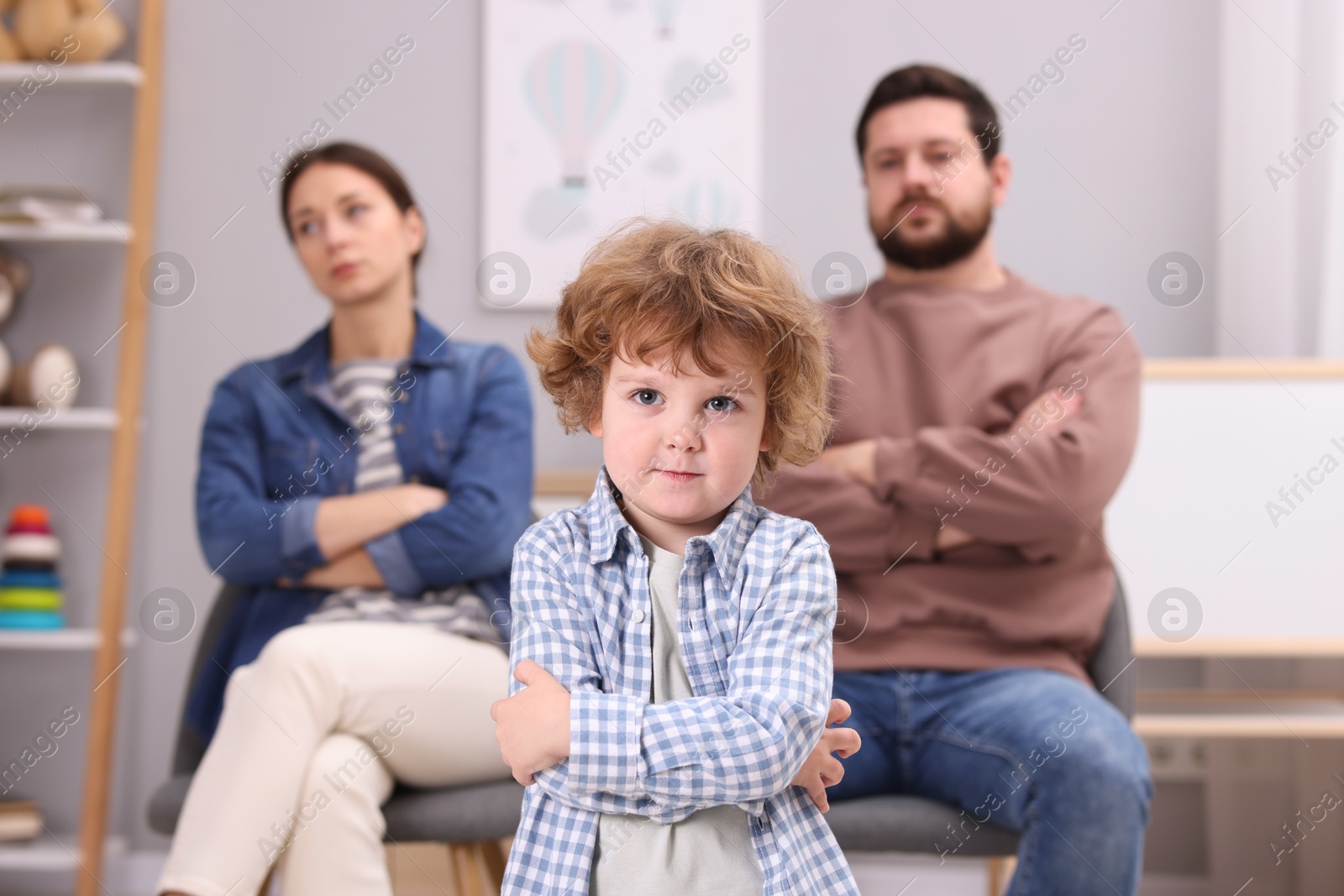 Photo of Resentful little boy and his parents arguing at home