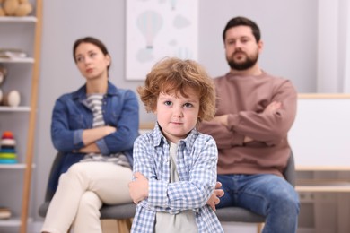 Photo of Resentful little boy and his parents arguing at home