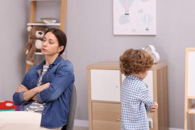 Photo of Resentful little boy and his mother arguing at home