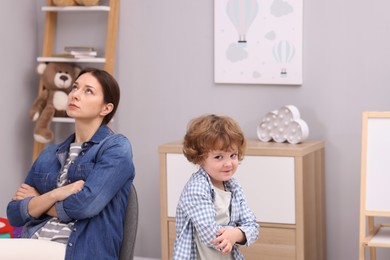 Photo of Resentful little boy and his mother arguing at home