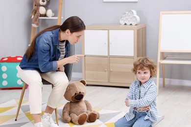 Photo of Resentful little boy and his mother arguing at home