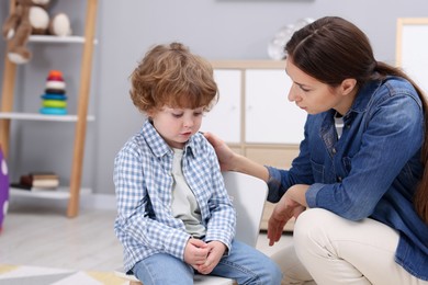 Photo of Resentful little boy and his mother arguing at home