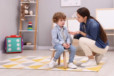 Photo of Resentful little boy and his mother arguing at home, space for text