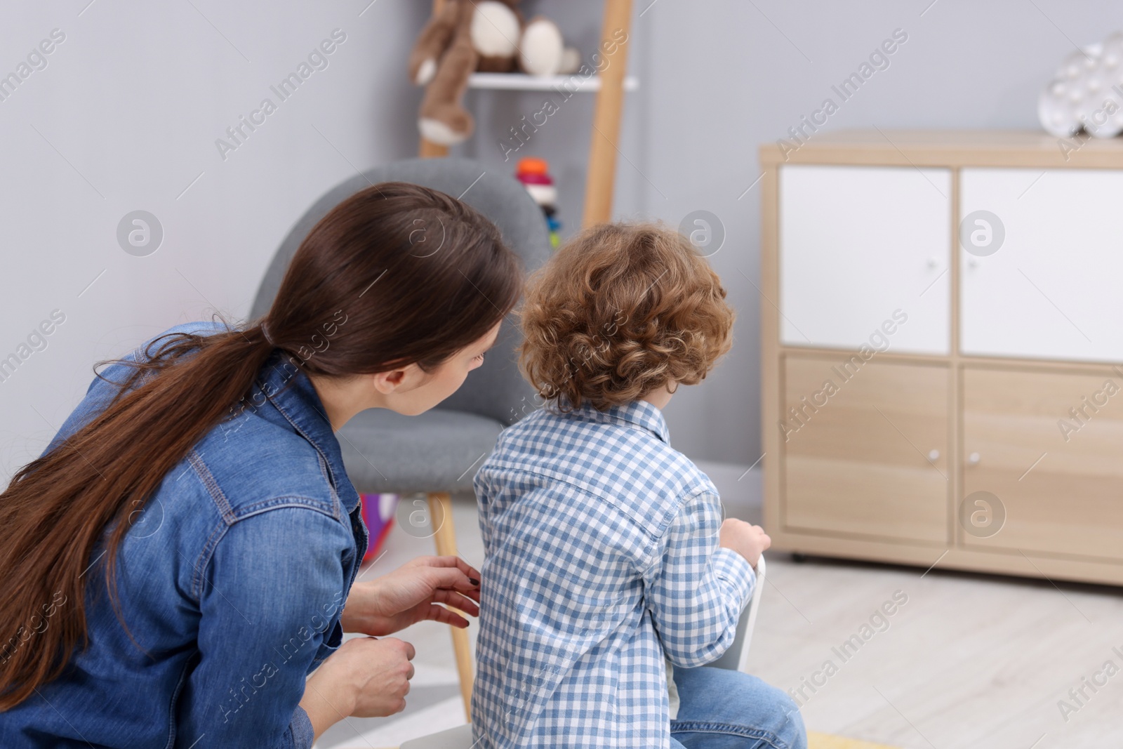 Photo of Resentful little boy and his mother at home, back view. Family dispute